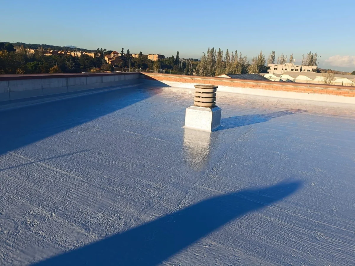 Impermeabilització d’una terrassa industrial a Terrassa amb acabat blau-gris i vistes a la ciutat